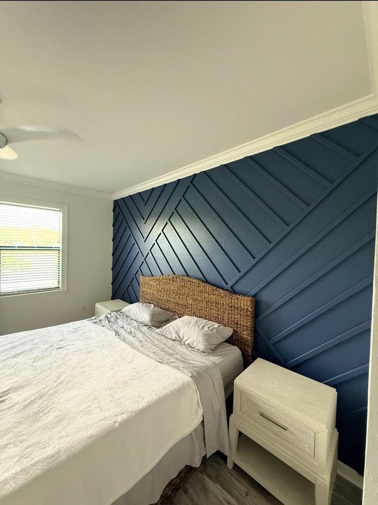 Navy blue geometric wood accent wall behind a bed