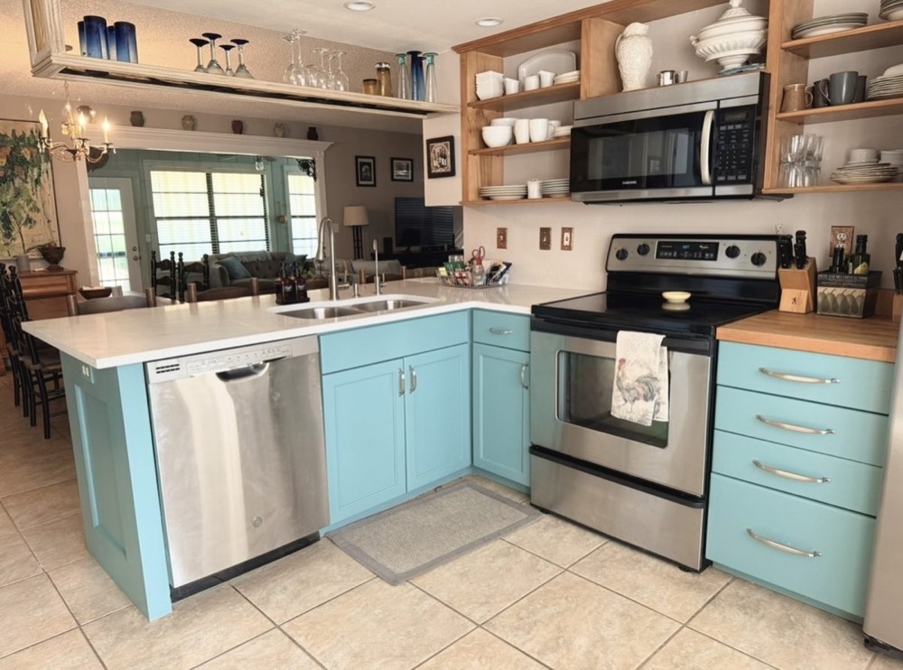Kitchen cabinets refinished in light teal with stainless appliances